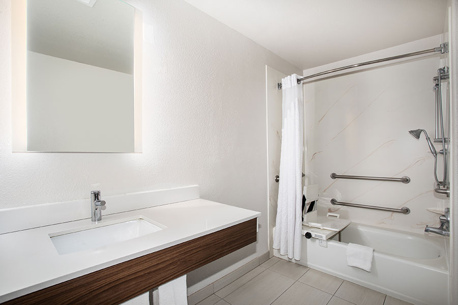 ADA accessible bathroom with accessible tub, grab bars, and shower seat